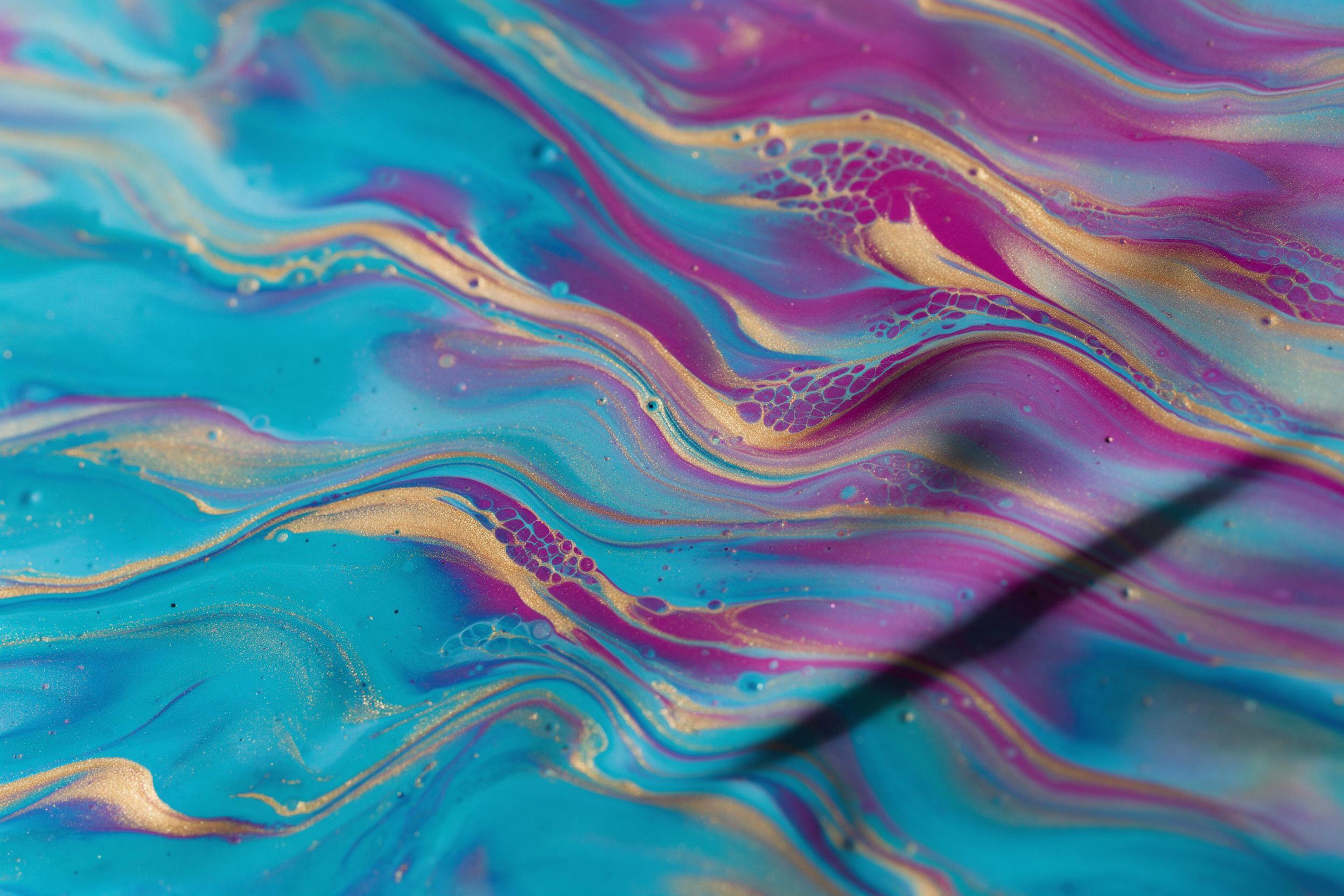Fluid acrylic pour art, swirling ribbons of electric cyan, magenta, and molten gold, intricate lacing cells, glossy resin surface, dramatic side lighting casting long shadows, macro view with shallow depth of field, soft reflections, no text, no brush strokes visible, serene minimal composition