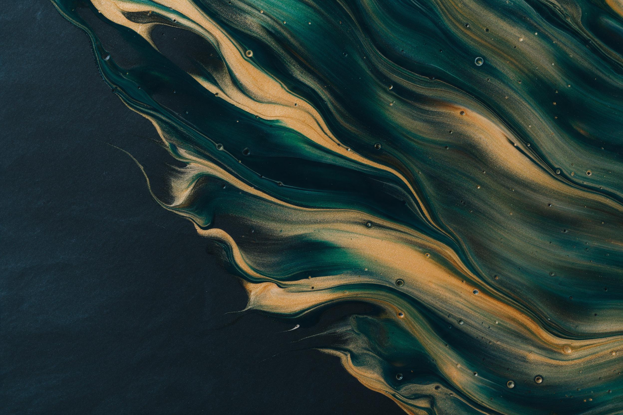 Fluid art of swirling golden and deep teal acrylic paints on dark slate surface, intricate marble-like veins, soft diffused studio lighting, glossy highlights, macro shot revealing delicate color gradients and tiny air bubbles, no text, minimalist composition with negative space.