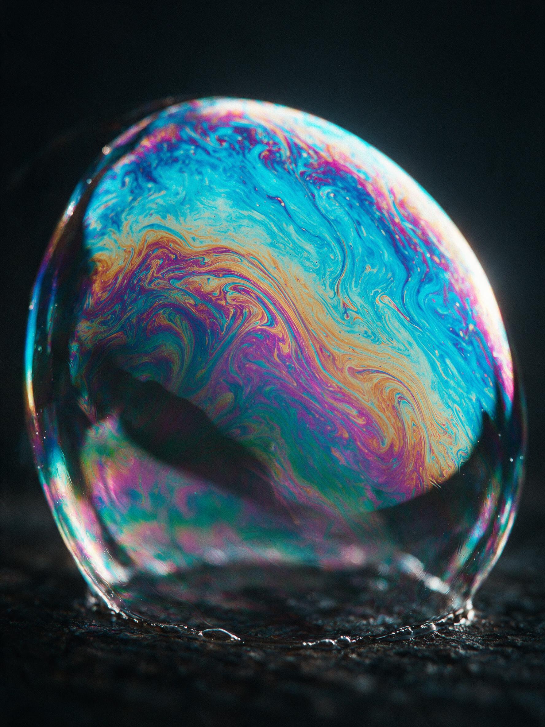 Close-up of a soap film in a dark studio, iridescent swirls of cyan, magenta, and gold, thin membrane ripples distorting light, macro lens, shallow depth of field, soft rim lighting from the side, subtle grain, no text or watermarks