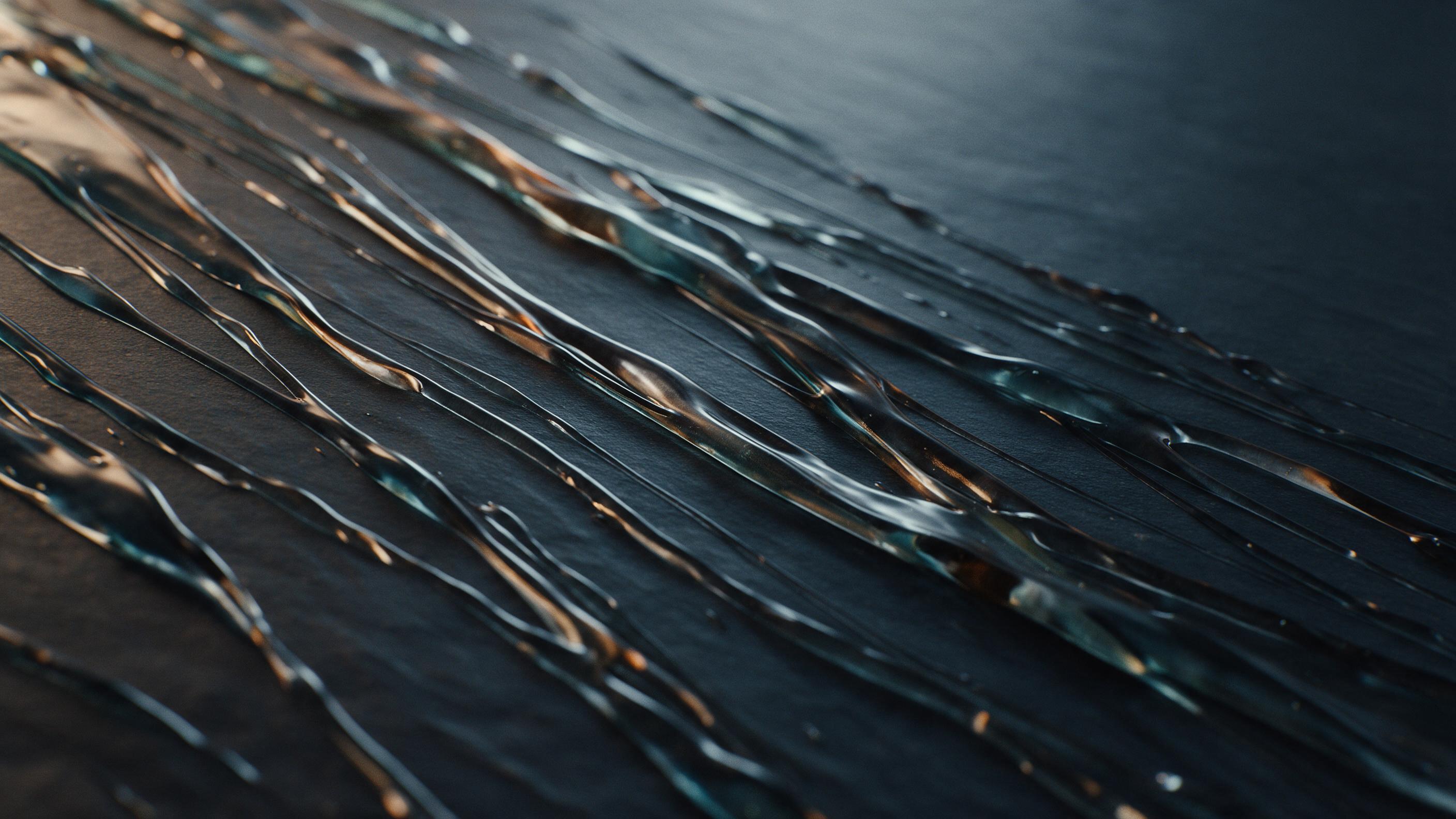 Diagonal streaks of molten glass interweave across a dark slate surface, catching amber and teal refractions from a low side light. Composition favors negative space at top right, with fine grain texture suggesting a slow shutter photograph. No text, no people, no grid patterns.