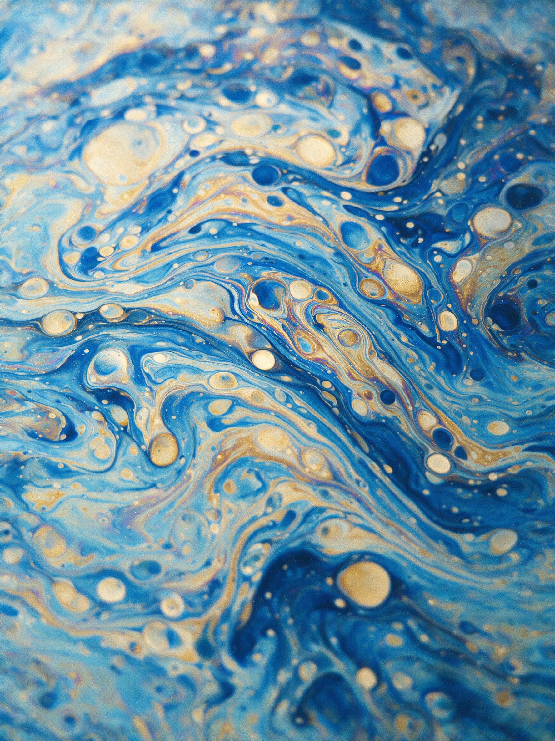 Macro shot of swirling oil and water, iridescent blues and golds, fluid marble patterns, soft diffused lighting, high contrast, minimal composition, no text or objects, subtle grain for texture